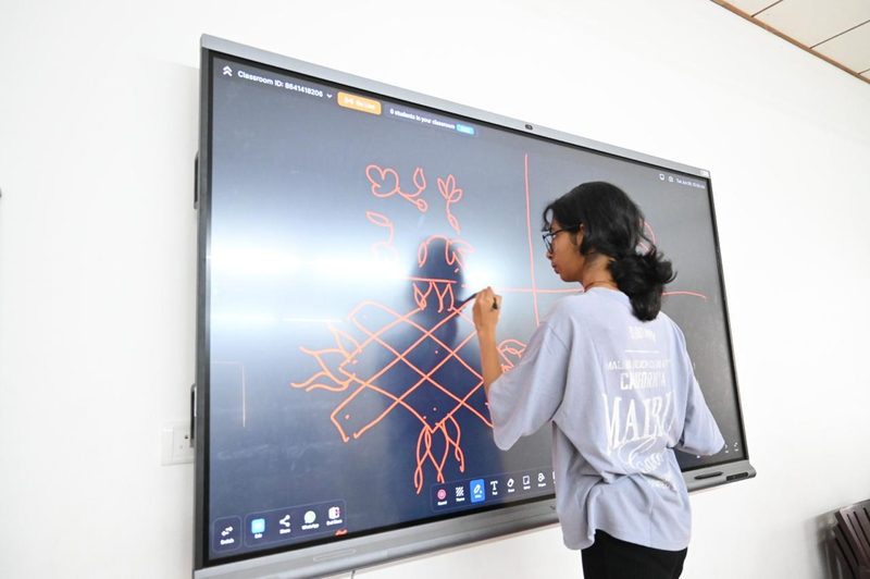 Shruti Arvind drawing a kolam pattern on the classroom screen