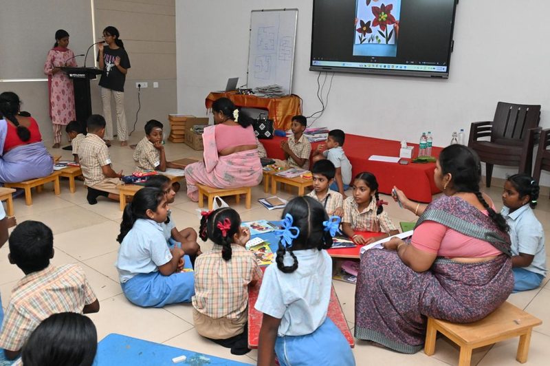 Children and teachers seated in groups at low tables during a workshop