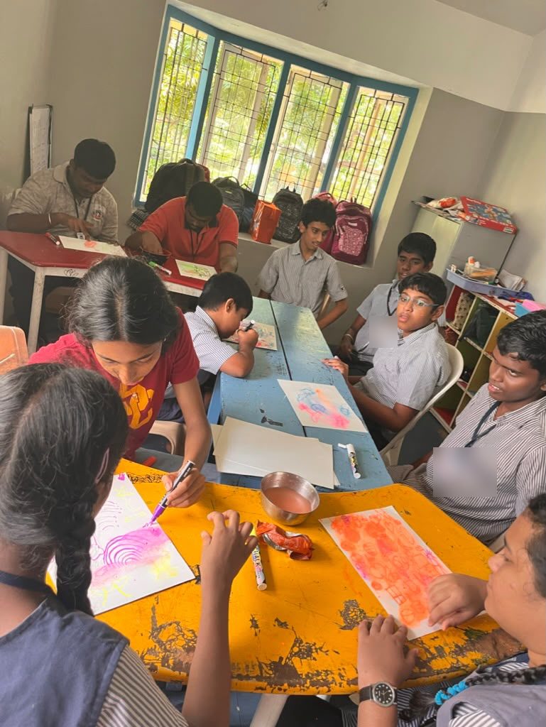 Students drawing with water-soluble chalk around a classroom table