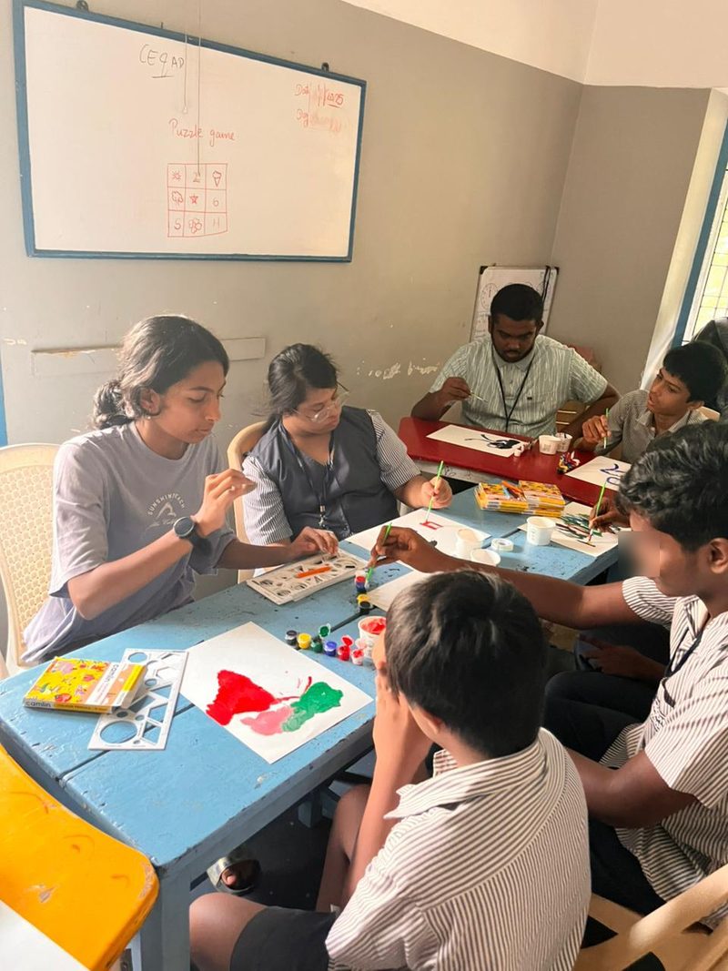 Shruti Arvind painting alongside students and a staff member