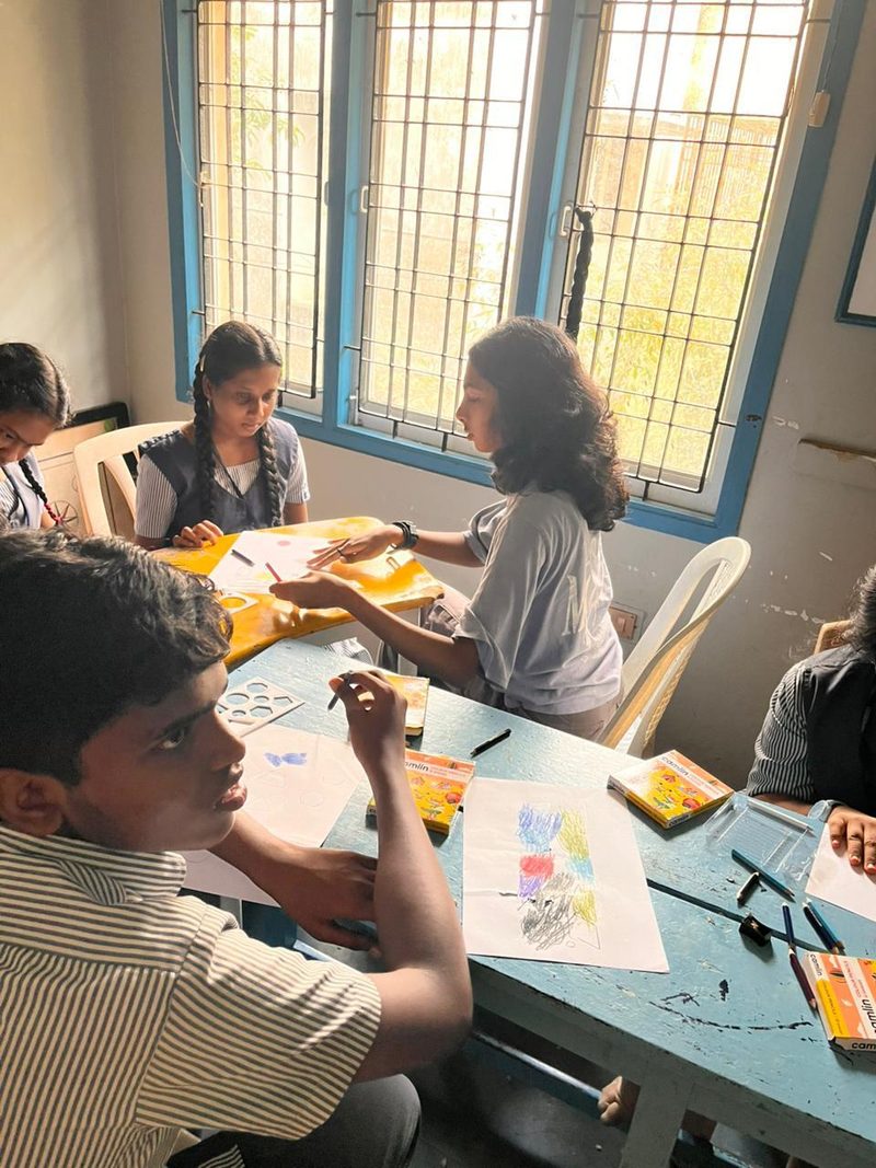 Shruti Arvind working with students at a table with stencils and crayons